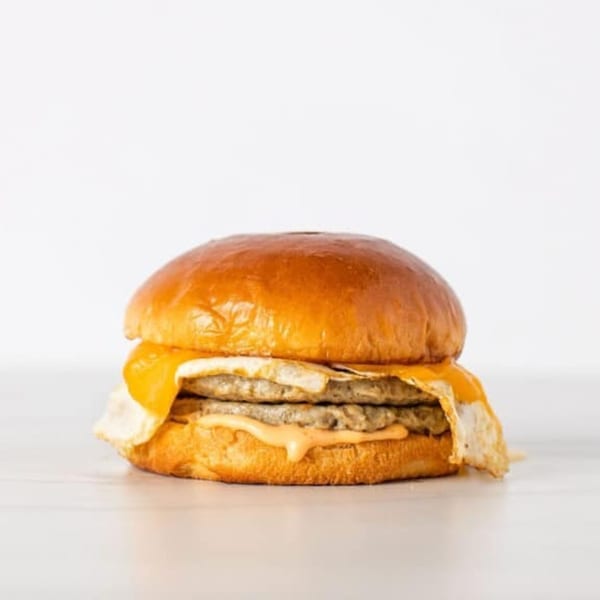 Effin Egg Yakima's breakfast sandwich with two sausage patties, egg, cheese, and sauce on a brioche bun.