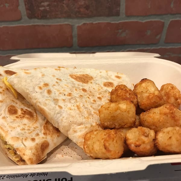 Effin Egg Yakima breakfast quesadilla with cheese and tater tots in a takeout container.