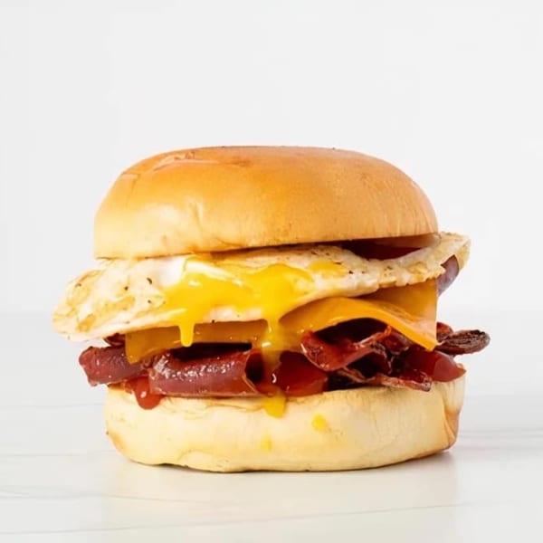 Effin Egg breakfast sandwich with runny fried egg, cheese, and bacon on a brioche bun.