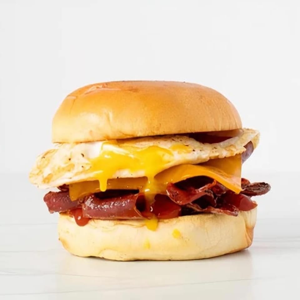 Effin Egg breakfast sandwich with runny fried egg, cheese, and bacon on a brioche bun.